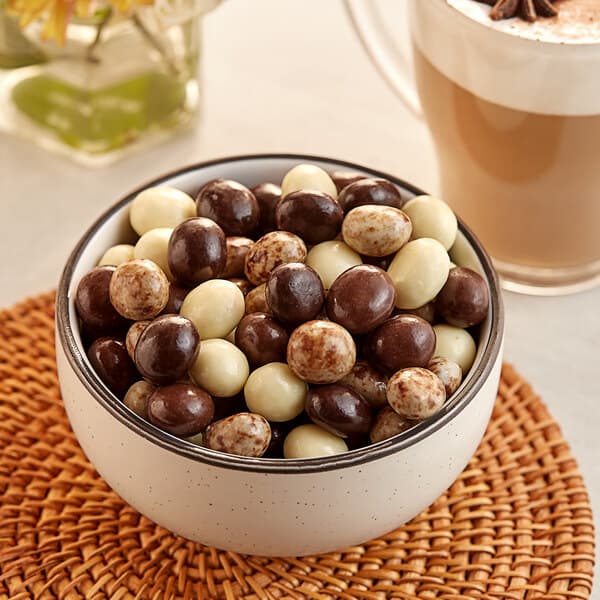 A bowl of assorted chocolate-covered espresso beans in various shades of brown and white.