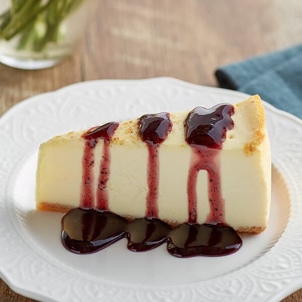 A slice of cheesecake topped with blueberry sauce on a white plate.